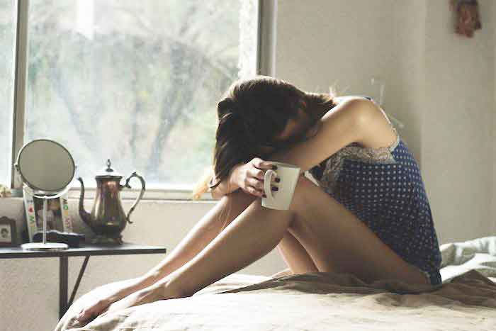 Girl Sitting on the bed with head down